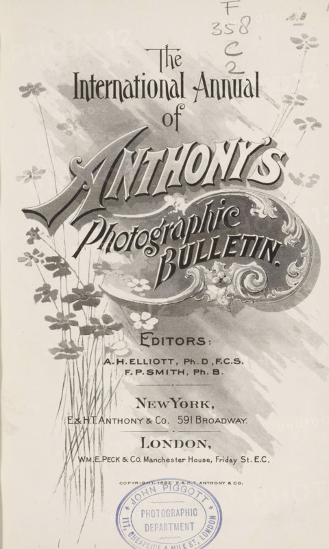 The international annual of Anthony's photographic bulletin, book, inscription: 'John Piggot Photographic department 117, Cheapside & milk St., London', editor (person who revises): Arthur H. Elliott, editor (person who revises): Francis P. Smith, publisher: E. & HT Anthony & Co., New York (city), publisher: WME Peck and Co., London, 1893 - 1895, Arthur H. Elliott, Francis P. Smith, E. & HT Anthony & Co., WME Peck and Co., editor (person who revises), publisher, North America, textile materials, pasteboard, paper, linen (material), printing, autotype, daylight gelatin silver print, photoaquatint, collotype, height 223 mm x width 149 mm x thickness 36 mm, A vertical vintage printed cover with ornate decorative lettering and flourishes occupying the upper and middle areas, surrounded by stylized floral illustrations with tall thin stems and clustered small flowers, a shaded background wash behind the main title, a block of smaller printed lines toward the lower center, and a circular sta...