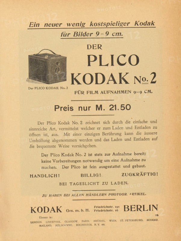 Reproduction of a landscape painting, reproduction, page, photomechanical print, photographer: Heinrich Kühn, cliché maker: anonymous, 1897, 1897 - in or before 1901, paper, autotype, height 69 mm x width 178 mm, landscapes, The image shows a vertically oriented aged paper page with printed text in a dark serif font and a small detailed illustration of a boxy camera with a handle and twin circular openings, positioned near the upper left. The paper has a warm beige tone with slightly darker edges and small flecks and spots. The layout includes large bold headings centered across the page and several paragraphs of smaller text beneath, with horizontal rule lines separating sections. Near the bottom there is a wider bold word set apart from surrounding text, and the overall appearance suggests a vintage advertisement or catalog page.