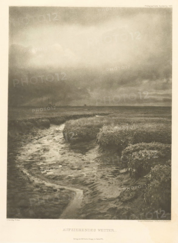 Aufziehendes Wetter, Landscape, with a ditch in the foreground, page, photomechanical print, photographer: Alfred Horsley Hinton, cliché maker: Meisenbach, Riffarth & Cie. (possibly), Berlin, publisher: Wilhelm Knapp Verlag, Halle an der Saale, 1897, 1897 - in or before 1901, printer (person), Saxony-Anhalt, paper, photoaquatint, height 199 mm x width 155 mm, behind semi-transparent cover with advertising message, landscapes, small canal, ditch, A monochrome image showing a marshy landscape with a winding water channel in the foreground leading toward a flat horizon, dense clumps of low vegetation flanking the channel, a wide expanse of cloudy sky occupying much of the upper area with darker clouds near the horizon, and a faint suggestion of distant shapes along the horizon line.