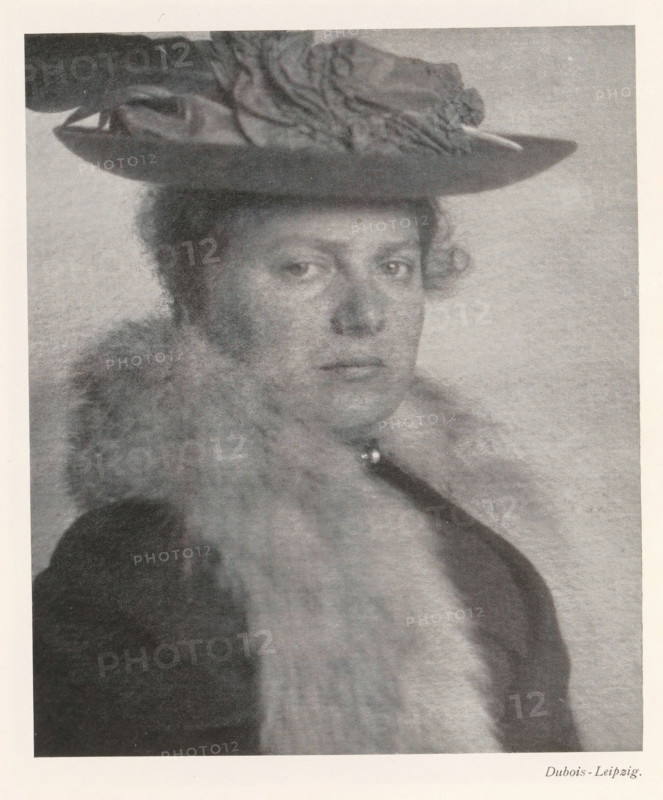 Portrait of an unknown woman, page, photomechanical print, photographer: Dubois, cliché maker: anonymous, c. 1898 - in or before 1903, paper, autotypie, height 167 mm x width 140 mm, Print on second unnumbered page after page 28., historical persons not known by name - BB - woman, A grayscale portrait of a person wearing a wide-brimmed hat with decorative fabric on top, showing a neutral facial expression and short curly hair at the temples, a fur or fluffy collar around the neck, and a dark coat or garment visible at the shoulders, all set against a plain light background.
