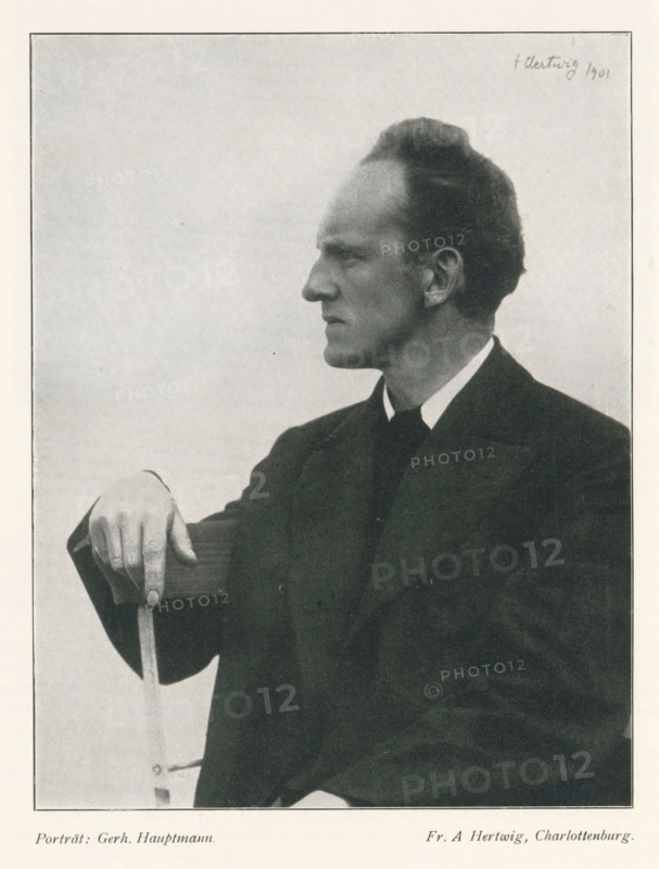 Portrait of Gerhart Johann Robert Hauptmann, Porträt: Gerh. Hauptmann, page, photomechanical print, photographer: Aura Hertwig, cliché maker: anonymous, 1901 - in or before 1903, 1901, paper, autotypie, height 169 mm x width 131 mm, Print on fourth unnumbered page after page 234., Person, Gerhart Hauptmann, historical persons, A black-and-white portrait of a man shown in profile facing left, wearing a dark suit jacket and a white-collared shirt, with his right arm resting on the back of a wooden chair and his hand gripping the top of the chair, his hair combed back and his expression neutral, set against a light, plain background.