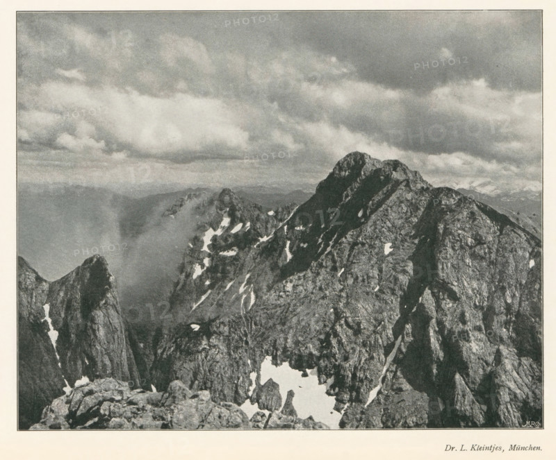 Mountain landscape, page, photomechanical print, photographer: LL Kleintjes, cliché maker: Meisenbach, Riffarth & Cie. (possibly), Berlin, c. 1898 - in or before 1903, paper, autotype, height 160 mm x width 201 mm, Print on fourth unnumbered page after page 290., mountains, A grayscale photographic image showing a rugged mountain range with steep, jagged peaks and rocky ridges, patches of snow nestled in crevices and on ledges, a distant layered horizon of softer mountains fading into the background, and a sky filled with textured clouds stretching across the upper portion of the scene.