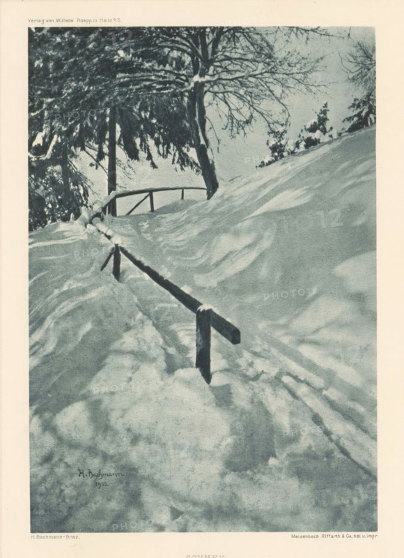 Schnee, Winter landscape, page, photomechanical print, photographer: Heinrich Bachmann, cliché maker: Meisenbach, Riffarth & Cie., Berlin, publisher: Wilhelm Knapp Verlag, Halle an der Saale, 1902 - 1903, 1902, printer (person), Saxony-Anhalt, paper, autotypie, height 179 mm x width 123 mm, Print six of fourteen prints at the back of the book., landscapes, snow, A snowy scene showing a sloping landscape with deep snow drifts and textured shadows, a simple wooden handrail running up the slope with snow accumulated on its posts and top, bare tree trunks and branches at the top of the slope with snow clinging to some limbs, denser evergreen branches partially covered in snow on the left, and a pale sky visible behind the trees.