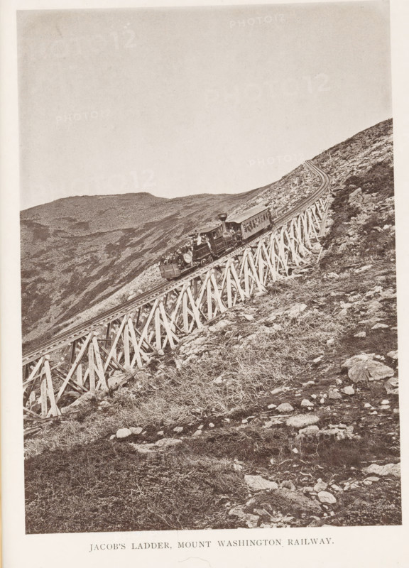 Jacob's Ladder, Mount Washington Railway, View of a train on a railway bridge on Mount Washington in the White Mountains, New Hampshire, page, photomechanical print, Washington, Mount, c. 1874 - in or before 1879, North America, Coos, paper, collotype, photogravure, height 178 mm, width 128 mm, Print for chapter 9., railway, train, mountains, bridge, A sepia-toned photograph of a steep hillside with a wooden trestle carrying a narrow railway track diagonally across the image from lower left to upper right, a small steam locomotive with an attached passenger car and an open-front car visible on the trestle, rocky terrain and sparse low vegetation on the slope surrounding the structure, and distant rounded mountain ridges in the background under a pale sky.