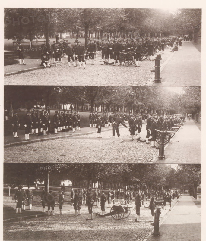 Three views of a military parade on the grounds of the United States Naval Academy in Annapolis, photograph, page, photographer: Edward H. Hart, United States Naval Academy, cliché maker: The Photo-gravure Co., New York (city), c. 1885 - in or before 1890, North America, Maryland, Annapolis, paper, collotype, photoprint, height 208 mm x width 176 mm, military parade, pageant, military academy, A sepia-toned photograph showing a tree-lined cobblestone street with rows of uniformed men standing and marching along the curb, several small wheeled cannons positioned on the roadway, some men holding poles or flags, groups of men clustered near the trees and on the sidewalk, a cast-iron fire hydrant or post visible near the curb, and buildings partially visible through the trees in the background.