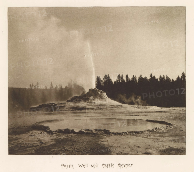 Castle Well and Castle Geyser, page, photomechanical print, photographer: Frank Jay Haynes, Yellowstone National Park, cliché maker: The Photo-gravure Co., New York (city), c. 1882 - in or before 1887, North America, paper, photoaquatint, height 175 mm x width 210 mm, hot spring, geyser, Castle Geyser, A sepia-toned landscape shows a steaming geothermal area with a rounded runoff basin in the foreground edged by a low, irregular rim; behind it a mound of mineral deposits rises with a narrow jet of water or steam shooting upward; a dark treeline silhouettes against a pale sky across the middle distance, and misty vapors drift around the mound and near the trees.