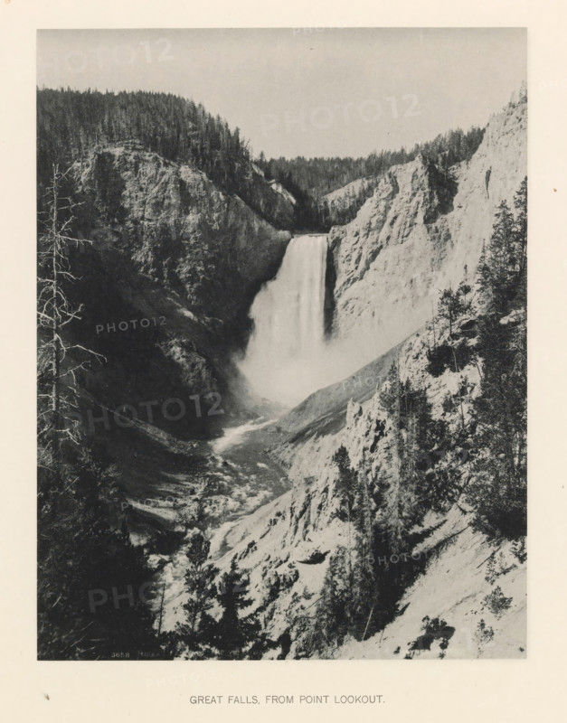 Great falls, from point lookout, page, photomechanical print, photographer: Frank Jay Haynes, Yellowstone National Park, cliché maker: The Photo-gravure Co., New York (city), c. 1886 - in or before 1891, North America, paper, collotype, photoprint, height 215 mm x width 165 mm, waterfall, Lower Yellowstone Falls, A tall waterfall drops between steep rocky cliffs into a misty plunge pool with a river flowing away through a narrow, rugged canyon; the cliff faces show textured rock and scattered trees, with denser forest visible along the canyon rim and a few bare tree trunks in the foreground.