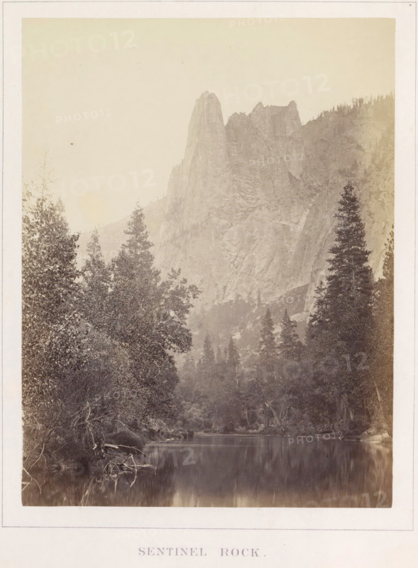 Sentinel Rock, View of Sentinel Rock in Yosemite Valley, photograph, page, number: 'IX.', photographer: Carleton E. Watkins, Yosemite Valley, c. 1860 - in or before 1868, North America, California, paper, albumen print, height 205 mm x width 156 mm, mountains, rock-formations, dale, valley, A tall, jagged granite rock formation rises from a rugged mountainside, its steep faces textured with visible cracks and ledges, surrounded by forested slopes with conifer trees along the ridge and valley; in the foreground a calm river reflects the trees and rocky banks, with leafy shrubs and tree roots along the water's edge and a mix of taller evergreens and dense undergrowth framing the scene.