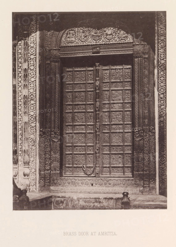 Brass door with plant and floral ornaments in Amritsar, Punjab, India, page, photomechanical print, title: 'BRASS DOOR AT AMRITZA.', number: 'X.', Amritsar, maker: Heliotype Printing Company, Boston (Massachusetts), c. 1875 - in or before 1885, photographer, North America, Massachusetts, paper, photoaquatint, height 220 mm x width 172 mm, ornament derived from plant forms, closed door, A tall ornate double door set within a richly carved stone frame, each door covered in square recessed panels filled with floral and foliate relief work, a heavy decorative ring handle suspended across the closed doors, flanked by intricately patterned vertical borders and pilasters with repeating geometric and floral motifs, a carved lintel and semicircular frieze above the doorway featuring sculpted figures and decorative relief, a stepped stone threshold and low plinth in front with small carved finials at the base, and surrounding masonry with varied textures and ornamental bands.