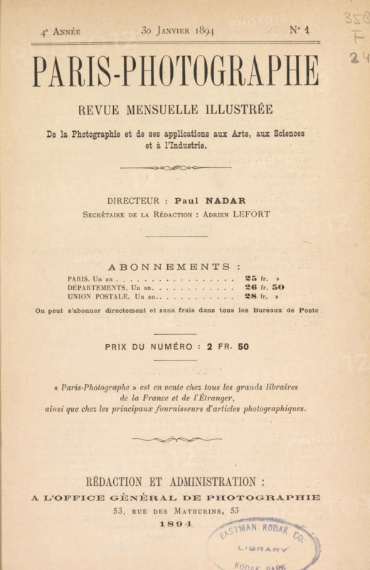 Paris-Photographe, magazine, editor (person who revises): Paul Nadar, 1894, editor (person who revises), pasteboard, biological material, paper, leather, photoaquatint, autotype, printing, collotype, height 273 mm x width 185 mm x thickness 50 mm, A yellowed printed page with a large centered title near the top in bold uppercase serif type, followed by several lines of smaller serif headings and centered lines, decorative horizontal rules, and blocks of printed text arranged in a formal layout; the paper shows slight age spots and a vertical crease, and a round blue oval stamp with faded ink appears near the lower right edge overlapping the bottom area.