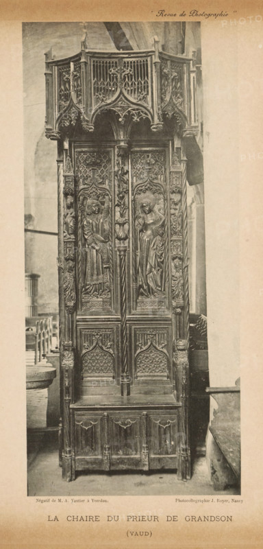 Pulpit, La chaire du prieur de grandson, page, photomechanical print, photographer: MA Vautier, cliché maker: Jules Royer, c. 1887 - in or before 1892, paper, collotype, photoprint, height 201 mm x width 91 mm, ambo, chancel, A tall intricately carved wooden chair or pulpit with ornate gothic detailing fills the frame, featuring a canopy with pointed arches and openwork tracery, carved figures and foliage motifs on the upper panels, and two central vertical panels each containing a carved standing figure within arched niches; flanking columns and side panels bear additional sculpted figures and decorative patterns, the lower section has arched carved panels and a bench-like base, and the piece stands on a stone floor with parts of surrounding stone architecture and seating visible at the sides.