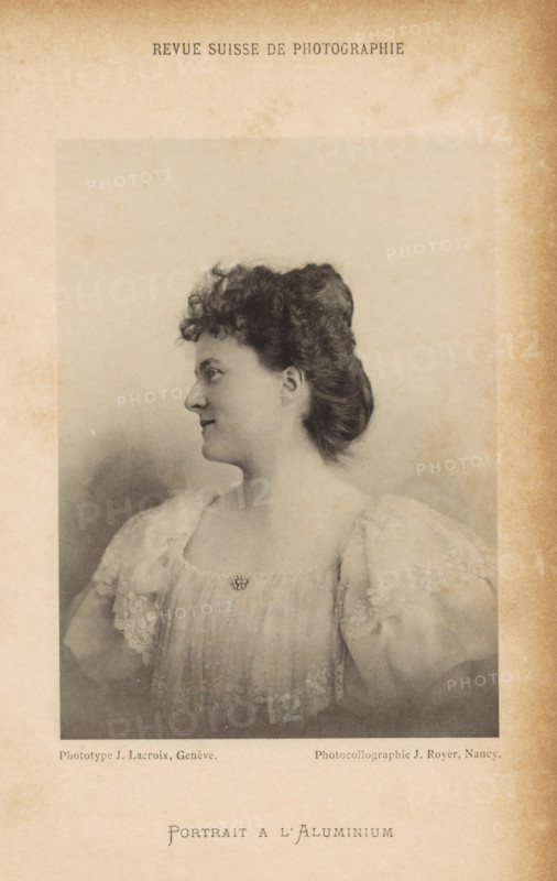 Portrait of an unknown woman, Portrait a l'Aluminium, page, photomechanical print, maker: J. Lacroix, maker: Jules Royer, c. 1892 - in or before 1897, J. Lacroix, Jules Royer, paper, collotype, photoprint, height 129 mm x width 94 mm, historical persons not known by name - BB - woman, A sepia-toned portrait of a woman shown in profile facing left, with curly hair swept up and a smooth neck; she wears a light, ornate dress with puffed, lacy sleeves and a small decorative brooch at the neckline, and the photograph is set within a faded, aged paper border with darker edges.