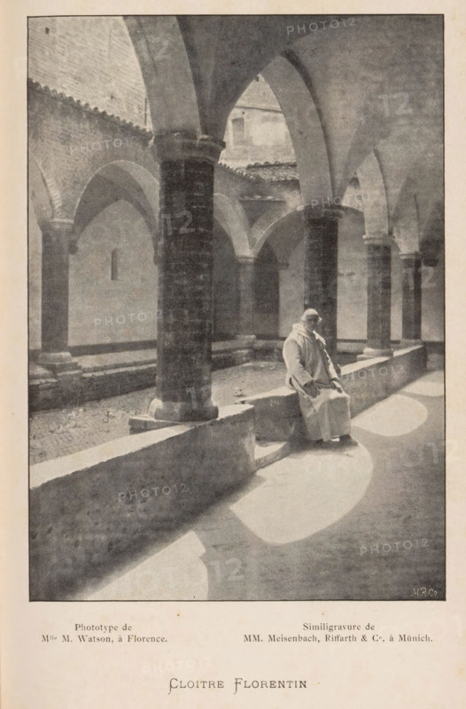 Cloitre Florentin, Monk in a Monastery in Florence, page, photomechanical print, maker: M. Watson, cliché maker: Meisenbach, Riffarth & Cie., Munich, c. 1894 - in or before 1899, Bavaria, paper, autotypie, height 155 mm x width 111 mm, monk(s), friar(s), cloisters, monastery, Florence, Tuscany, A grayscale photograph of a cloister courtyard with stone arches and columns surrounding an open central area, showing a long low stone bench running along the colonnade; a person wearing a long light-colored robe and head covering sits on the bench near a column, facing slightly toward the camera with hands resting on their lap; sunlight casts curved bright patches on the floor of the covered walkway and creates soft shadows from the arches and columns; the stone surfaces of walls, columns, and benches show textured weathering, and the upper parts of the courtyard reveal tiled roof edges and a small rectangular opening in a distant wall.
