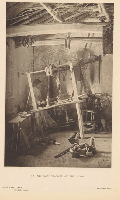 Woman working with a loom, An Azorean Peasant at the Loom, page, photomechanical print, photographer: Walter B. Swift, cliché maker: Frederick Gutekunst, Philadelphia, c. 1887 - in or before 1892-04-16, printer (person), North America, paper, collotype, photoprint, height 178 mm x width 115 mm, weaving-loom (women (labourers)), A sepia-toned scene shows an interior room with a wooden loom occupying the center, its frame of rough beams and suspended threads visible, and a seated woman working at the loom with a long skirt and hair pulled back; earthen walls with peeling plaster form the backdrop, a thatched ceiling with exposed rafters and hanging dried ears of corn runs across the top, and various tools and objects are scattered around the floor including a spinning wheel, a low table with a basket, sandals, a pair of shoes, a bottle-shaped vessel, and a small basket filled with fabric or yarn, while ropes, bundles of fiber, and wooden implements hang from or lean against the loom and ...