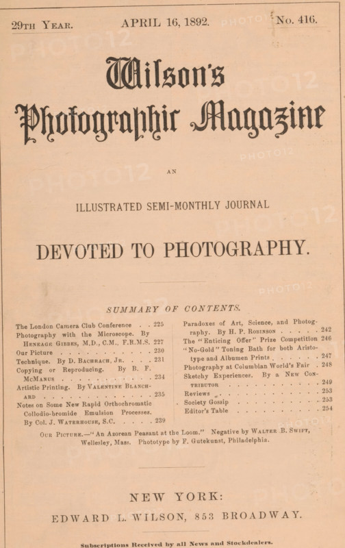 Wilson's photographic magazine, magazine, publisher: Edward Livingston Wilson, New York (city), 1892-04-16, Edward Livingston Wilson, publisher, North America, paper, printing, wood engraving, autotype, collotype, height 256 mm x width 176 mm x thickness 4 mm, The image shows a faded, sepia-toned page with ornate large blackletter headings near the top and a centered, bold serif line below, followed by several columns of smaller printed blocks and a thin ruled border around the page edges. The top area contains a narrow band with smaller text-like marks and a faint rectangular blemish near the upper right. The central area is dominated by wide empty space between the prominent headings and the denser printed blocks below. The lower half displays two columns of tightly set lines and small dots, with faint smudges and aging marks scattered across the paper, and a larger bold line near the bottom above a final centered line of larger serif type. The paper shows slight discoloration, creas...