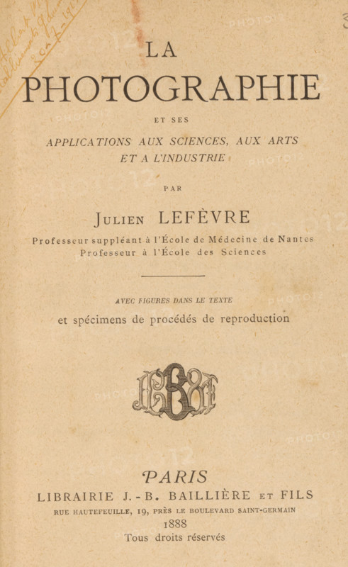 La photographie et ses applications aux sciences, aux arts et à l'industrie, book, annotation: 'June 1999, ... April 1993', annotation: '..., ..., 20-7-1915', writer (clerical worker): Julien Lefèvre, publisher: JB Baillière et Fils, Paris, in or before 1888, Julien Lefèvre, JB Baillière et Fils, writer (clerical worker), publisher, pasteboard, biological material, leather, paper, printing, height 197 mm x width 136 mm x thickness 31 mm, The image shows an aged book title page printed on beige, textured paper with a large heading centered near the top and several lines of smaller printed text beneath it; there is a decorative monogram-like emblem midway down the page, a horizontal rule above a short line of small italicized text, and a faint diagonal handwritten mark near the upper left corner; the printing uses serif fonts in varying sizes and weights and the page exhibits subtle age spots and discoloration.