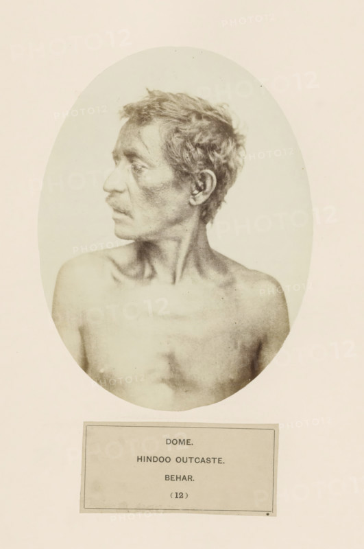 Portrait of an unknown man from the Dom community of Bihar in eastern India, photograph, page, inscription: 'DOME., HINDOO OUTCASTE., BEHAR.', number: '(12)', Bihar, c. 1858 - in or before 1868, photographer, North India, paper, albumen print, height 159 mm x width 120 mm, human races, peoples, nationalities, A sepia-toned oval portrait of a shirtless man shown from the shoulders up, facing left in profile, with short tousled hair, a thin mustache, defined collarbones, and a lean neck, set against a pale background and mounted above a rectangular plaque.