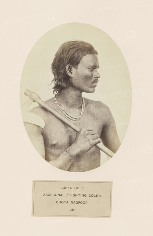 Potrait of an unknown man from the Ho tribe of Chota Nagpur in eastern India, photograph, page, The Ho tribe is also known as Lurka Kol., inscription: 'LURKA COLE., ABORIGINAL ('FIGHTING COLE')., CHOTA NAGPOOR.', number: '(18)', photographer: Benjamin Simpson (possibly), Chota Nagpur, c. 1858 - in or before 1868, Jharkhand, paper, albumen print, height 160 mm x width 120 mm, human races, peoples, nationalities, A sepia-toned oval portrait of a shirtless man shown in profile facing right, with medium-length dark hair, a mustache, and a beaded necklace, holding a long-handled object across his shoulder with one hand gripping the shaft and the other resting lower on the shaft, set against a plain light background and mounted on a larger pale sheet.
