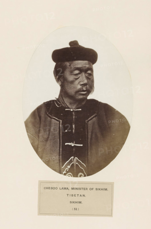 Portrait of a minister of Sikkim, photograph, page, inscription: 'CHEBOO LAMA, MINISTER OF SIKHIM., TIBETAN., SIKHIM.', number: '(51)', photographer: Benjamin Simpson (possibly), Sikkim, c. 1858 - in or before 1868, paper, albumen print, height 173 mm x width 127 mm, human races, peoples, nationalities, An oval-framed sepia portrait of an older man shown from the chest up wearing a dark rounded hat and a dark robe with lighter trim and decorative fastenings, his face turned slightly to the side with a neutral expression, visible facial hair including sideburns and a mustache, and a plain light background surrounding the oval.