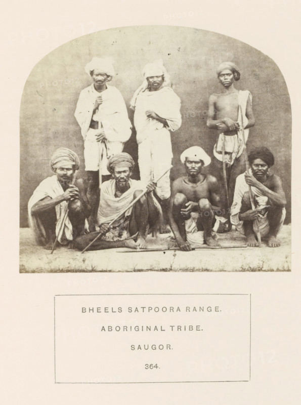 Portrait of a group of people from the Bhil tribe of the Satpura mountains, Sagar, Madhya Pradesh, India, photograph, page, number: '364.', inscription: 'BHEELS SATPOORA RANGE., ABORIGINAL TRIBE., SAUGOR.', photographer: James John Waterhouse (possibly), 1862, Central India, paper, albumen print, height 97 mm x width 107 mm, human races, peoples, nationalities, A sepia-toned photograph shows a group of seven men arranged in two rows against a plain backdrop, with three standing in the back and four seated or squatting in the front on a raised narrow platform; the men wear varied headwraps and cloth draped around their bodies, some covering shoulders and torsos while others are bare-chested, and several hold long wooden staffs or sticks; facial hair varies among them, and their expressions are neutral; the image is bordered by a rounded arch at the top and has a blank area beneath the photograph.
