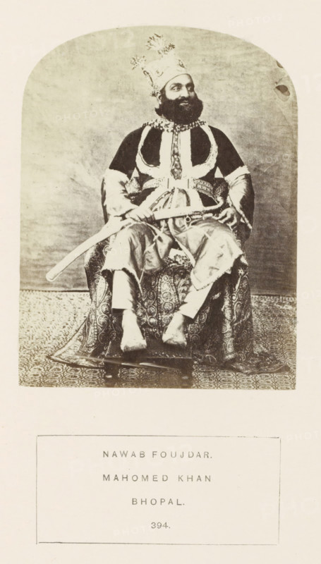 Portrait of Mahomed Khan, an officer at Sekunder Begum, a queen of Bhopal, Madhya Pradesh, India, photograph, page, number: '394.', inscription: 'NAWAB FOUJDAR., MAHOMED KHAN., BHOPAL.', photographer: James John Waterhouse (possibly), Bhopal, 1862, Central India, paper, albumen print, height 115 mm x width 88 mm, ruler, sovereign, human races, peoples, nationalities, A sepia-toned portrait shows a bearded man seated on a patterned chair, wearing an ornate tall headdress with decorative plumes, a dark robe with light trim and an embellished collar, and loose trousers; he holds a curved sword across his lap and rests his hands on its hilt, while a richly patterned textile covers the chair and floor beneath him and a plain backdrop fills the space behind.