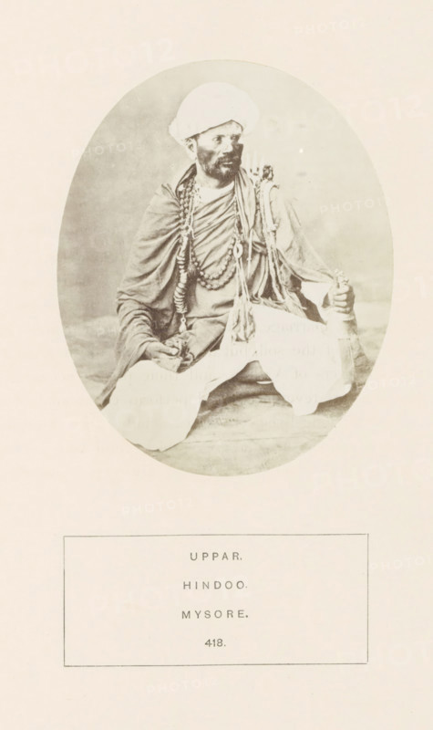 Portrait of an unknown man from the Uppara community of Mysore, Karnataka, India, photograph, page, number: '418.', inscription: 'UPPAR., HINDOO., MYSORE.', Mysore, c. 1865 - in or before 1875, photographer, South India, paper, albumen print, height 107 mm x width 88 mm, head-gear: turban, human races, peoples, nationalities, An oval sepia photograph shows a seated man wearing a turban and layered draped garments, with multiple long beaded necklaces and decorative cords around his neck and shoulders; he has a beard and moustache and is looking slightly to one side, one hand resting on his knee and the other holding a cylindrical object, while the background inside the oval is plain and the photograph is mounted on a light rectangular page.