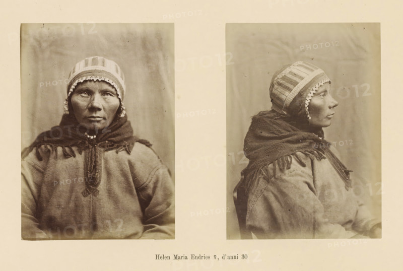 Helen Maria Endries ?, d' anni 30, Two portraits of Helen Maria Endries, page, Left a front view, right a side view., number: 'Tavola XXII.', photographer: Paolo Mantegazza, Scandinavia, photographer: Carlo Pietro Stefano Sommier, c. 1870 - in or before 1880, Paolo Mantegazza, Carlo Pietro Stefano Sommier, paper, albumen print, height 254 mm x width 340 mm, Photo in photo section at the back., adult woman (sideview, profile), adult woman (front view), Two sepia-toned portraits of the same woman are shown side by side on a light background; the left portrait is a frontal view and the right portrait is a profile view facing right. The woman wears a patterned cap with a scalloped edge and a dark shawl wrapped around her shoulders and neck. Her clothing appears textured and layered with visible stitching and fringed edges on the shawl. The woman's face shows a neutral expression, and fine facial lines and shadows are visible. The backdrop behind her is plain and softly mottled.
