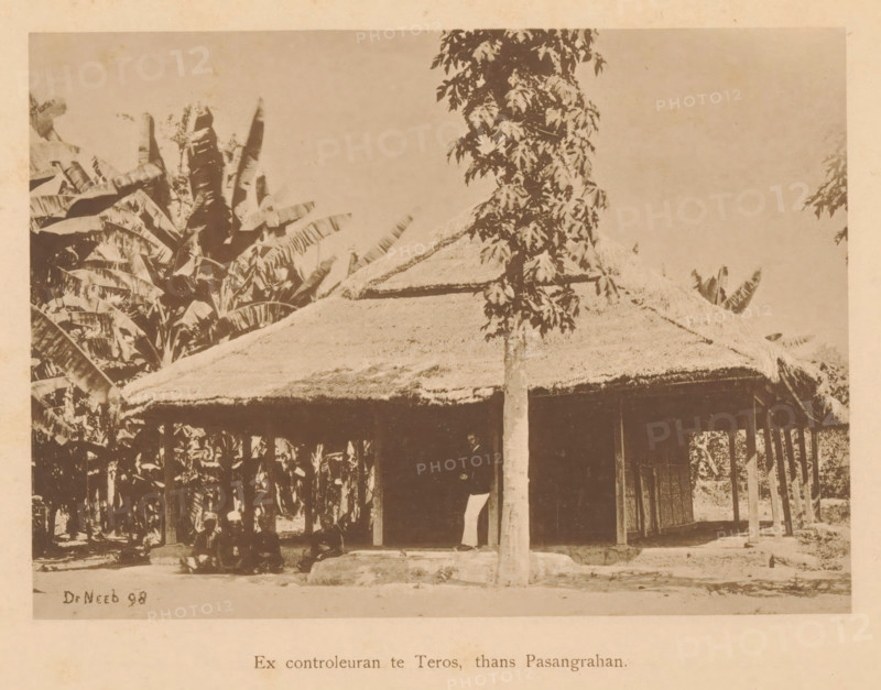 Ex inspector in Teros, now Pasangrahan, View of four unknown persons sitting in front of a house, page, photomechanical print, maker: Christiaan Johan Neeb, c. 1892 - in or before 1897, paper, collotype, photoprint, height 122 mm x width 163 mm, historical persons, other dwelling types, Indonesia, A sepia-toned photograph showing a thatched-roof structure with a sloping straw roof supported by slender wooden posts, a tall slender tree with clustered leaves standing in front of the structure, dense large-leaved plants and banana-like foliage surrounding and rising behind the building, shaded open area beneath the roof where a piece of fabric or cloth hangs and a shadowed entrance is visible, a raised earthen or stone base at the tree trunk, and a plain sky occupying the upper background.