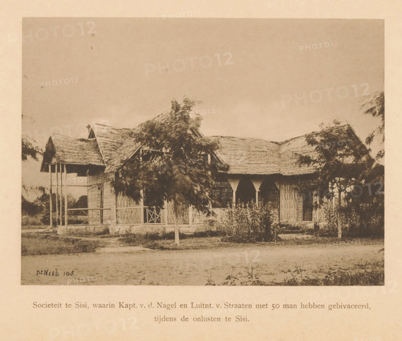 View of a society in Sisi, Society in Sisi, in which Capt. vd Nagel and Luitnt. v. Streets with 50 men bivacated during the unrest in Sisi, page, photomechanical print, maker: Christiaan Johan Neeb, c. 1892 - in or before 1897, paper, collotype, photoprint, height 122 mm x width 166 mm, landscape with ruins, Indonesia, A sepia-toned photograph shows a single-story building with a thatched roof and woven walls, partially obscured by leafy trees and shrubs in front; the structure features open archways and a small porch area with vertical supports, and there is a grassy area and a dirt path in the foreground.