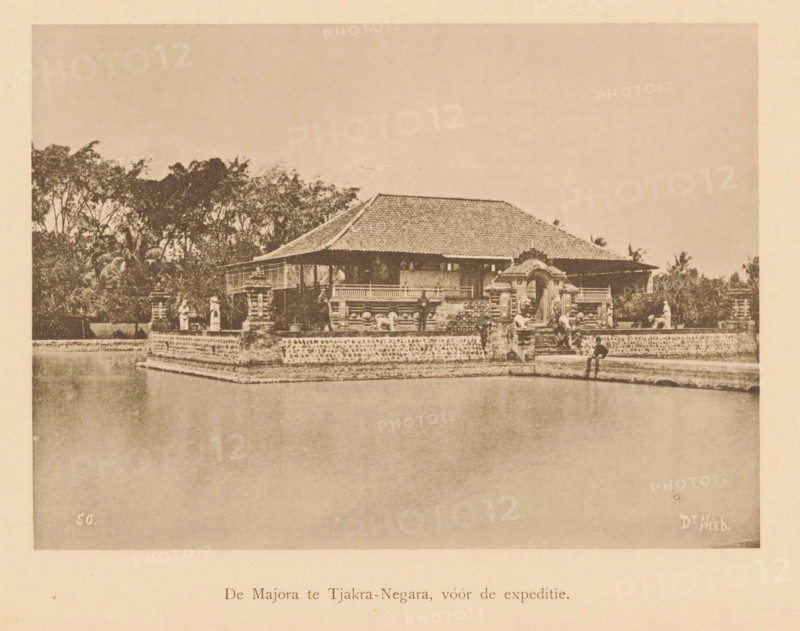View of a temple on the bank of a river, Majora at Tjakra-Negara, before the expedition, page, photomechanical print, maker: Christiaan Johan Neeb, c. 1892 - in or before 1897, paper, collotype, photoprint, height 121 mm x width 166 mm, river bank, temple, shrine, non-Christian religions, Indonesia, A sepia-toned photograph showing a low building with a tiled roof set on a raised stone platform surrounded by water, ornamental stone railings and carved gate structures in front, trees and foliage behind the building, small human figures positioned along the platform near the gate and edges, and a person seated at the platform edge with legs hanging toward the water.