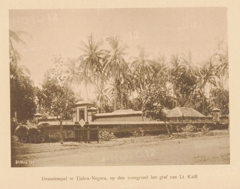 Dessa temple in Tjakra-Negara, in the foreground the grave of Lt. Kalff, View of the Dessa Temple and the grave of Lieutenant Kalff, page, photomechanical print, maker: Christiaan Johan Neeb, c. 1892 - in or before 1897, paper, collotype, photoprint, height 119 mm x width 161 mm, trees, grave, tomb, temple, shrine, non-Christian religions, Indonesia, A sepia-toned photograph showing a low wall and gate in front of a compound with a small tower-like entrance and a thatched-roof structure behind it, dense vegetation and tall palm trees rising behind the buildings, a dirt foreground with scattered vegetation, and a pale border surrounding the image.