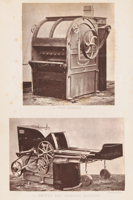 View of a rag shaking machine, 1. Rag Shaker, page, photomechanical print, photographer: Appleton & Co., cliché maker: Woodbury Permanent Photographic Printing Company, Bradford (England), c. 1871 - in or before 1876, paper, Woodburytype, Woodburytypepie, height 102 mm x width 92 mm, machine driven by human or animal power, A sepia-toned photograph shows two large industrial machines stacked vertically within a single frame on a pale background. The upper machine has a boxy base with a curved top and exposed slatted interior, a large circular wheel on its side connected to a belt, a hinged perforated panel at the front, and vertical supports with rounded tops. The lower machine displays a long horizontal bed with a curved housing at one end, multiple toothed and spoked wheels of varying sizes, connecting rods and levers, a rectangular upright casing near its center, and two round weights suspended near the far end; both machines rest on a textured floor with scattered small metal parts...