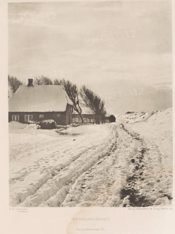 Winter landscape, Winterlandschaft, page, photomechanical print, inscription: 'Photogr. Mitteilungen XL', photographer: HM Carstensen, cliché maker: Büxenstein & Comp., Georg, c. 1898 - in or before 1903, paper, photoaquatint, height 169 mm x width 133 mm, landscapes, snow, A snowy rural scene with a thatched-roof cottage on the left partially covered in snow, a dark chimney atop the roof, and windows along the cottage wall; leafless trees stand beside and behind the cottage, their bare branches reaching upward; a snow-covered path with deep rutted tire or sled tracks runs from the foreground toward the horizon on the right, bordered by snow banks and gentle rises; scattered snowdrifts and footprints are visible across the ground; the sky above is pale and overcast with subtle cloud texture and ample empty space.