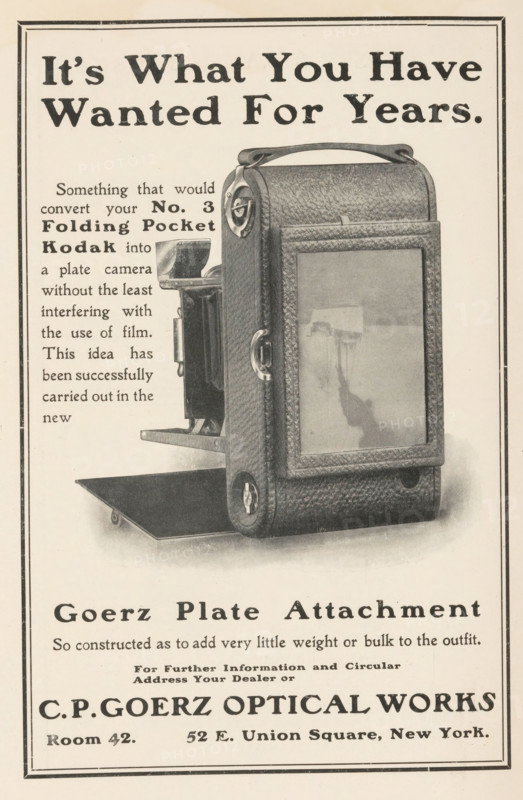 View of the back of a Kodak camera, page, photomechanical print, c. 1897 - in or before 1902, paper, autotype, height 108 mm x width 99 mm, Print in a section of advertisements at the back of a book. Print is part of an advertising message from CPGoerz Optical Works., camera, photography, A vertically oriented vintage advertisement showing a textured leather camera case with a handle and metal clasps partially open to reveal an inner camera mechanism and a folding platform, photographed against a light background with a double-lined border.