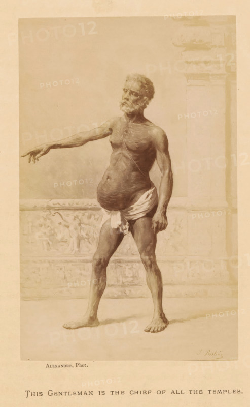 This Gentleman is the Chief of All the Temples, Photo reproduction of This Gentelman is the Chief of All the Temples by Jean Baptiste Robie, photograph, reproduction, page, photographer: Alexandre, after painting by Jean Baptiste Robie, c. 1878 - in or before 1883, paper, albumen print, height 153 mm x width 97 mm, adult man, A sepia-toned illustration shows an older barefoot man standing with one arm extended to the side and the other hanging by his hip, his body partially draped with a cloth around his waist, a rounded abdomen and visible musculature, a beard and short hair, and a thin strap across his chest; he stands in front of a low decorative wall with carved relief and a tall column to the right, all set against a plain background.