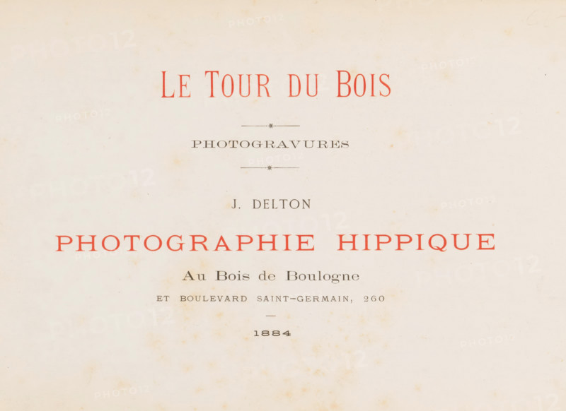 Le tour du bois photogravures, book, photographer: Jean Delton, 1884, textile materials, pasteboard, linen (material), paper, photoaquatint, height 215 mm x width 320 mm x thickness 20 mm, A cream-colored paper sheet with scattered light brown spotting and aging marks, featuring a centered layout of printed lines and decorative short horizontal rules, some printed in faded red ink and others in dark gray, with varying font sizes and spacing, and a larger block of red text spanning across the middle, all set against a slightly uneven off-white background.