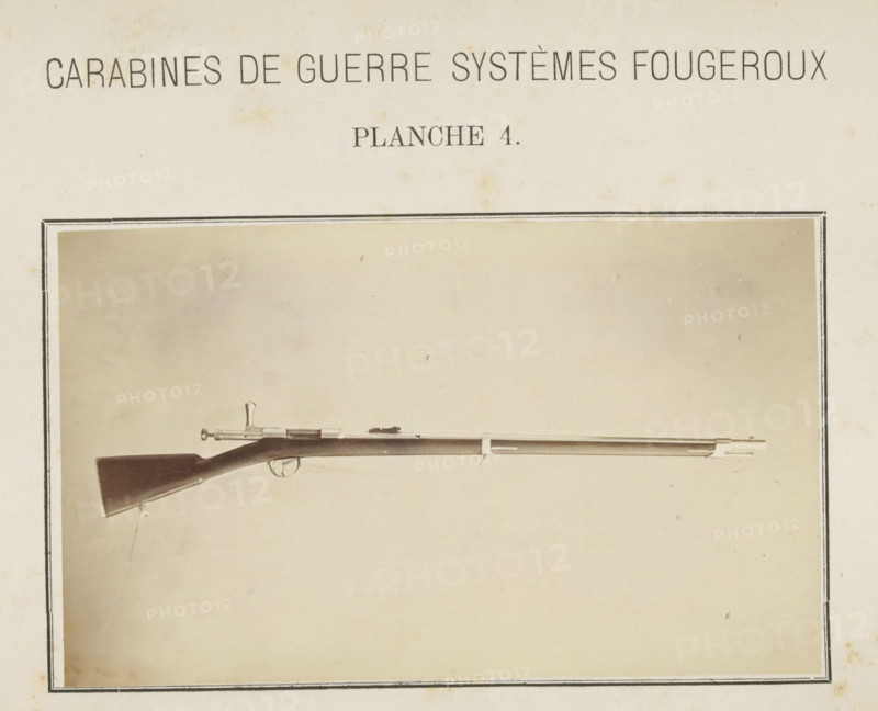 Rifle, photograph, page, number: 'Planche 4.', inscription: 'Carabines de guerres systèmes Fougeroux', photographer: Edouard Magis, Liège, c. 1857 - in or before 1867, paper, albumen print, height 159 mm x width 97 mm, Image in section at the back., A sepia-toned photograph shows a long rifle positioned horizontally within a rectangular frame; the rifle has a dark wooden stock with a curved butt, a metal trigger guard and bolt action near the stock, a long slender barrel with metal fittings and a front sight, and small hanging straps attached beneath the stock, all set against a plain light background with mild discoloration and a thin decorative border around the image.