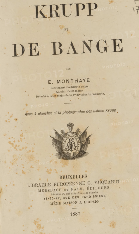Krupp et de Bange, par E. Monthaye, book, annotation: 'MAR, 2000', writer (clerical worker): E. Monthaye, publisher: Charles Muquardt, Brussels, 1887, writer (clerical worker), textile materials, pasteboard, paper, linen (material), printing, decorated paper, lithography, albumen print, height 217 mm x width 144 mm x thickness 24 mm, The image shows an aged book page with a large title area at the top and smaller lines of printed text below, all on yellowed paper that has numerous brownish foxing spots and stains scattered across the surface; near the center there is a decorative emblem featuring a circular medallion with ornate detailing and draped flags, and below that the page continues with more printed lines and additional foxing, the overall appearance showing worn edges and a vertical orientation.