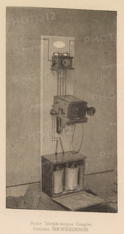Complete telephone set, Poste Téléphonique Complet, page, photomechanical print, inscription: 'Système VAN RYSSELBERGHE', cliché maker: Bauwens (possibly), c. 1880 - in or before 1885, photographer, paper, photoaquatint, height 168 mm x width 93 mm, telephone, post, telegraph and telephone, means of communication, A vertical panel mounted against a wall holds a wall-mounted box with a round mouthpiece and two small bells on top connected by zigzag coiled wires down to a larger rectangular box below; the lower box has a crank handle on its side and a curved support bracket beneath it, with a cord hanging down to an open-topped wooden cabinet at the base that contains two cylindrical containers and a removable lid resting on the floor in front; the scene is rendered in a sepia-toned, grainy illustration style.