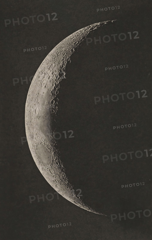 View of the moon, Photographie lunaire obtenue a l'observatoire de Paris, page, photomechanical print, inscription: 'Société Belge d'Astronomie Atlas Lunaire Pl. C.', inscription: '1897. Mars 7. _ 6.H 5. Temps Moyen de Paris, Age 4 jours 6.4 heures', photographer: Loewy et Puiseux, photographer: Maurice Loewy, photographer: Pierre Henri Puiseux, cliché maker: J. Heuse, 1897-03-07 - in or before 1898, printer (person), paper, photoaquatint, height 199 mm x width 127 mm, moon as celestial body, A close-up view of a crescent-shaped celestial surface against a dark background, showing a textured terminator with numerous circular impact depressions and raised rims, rough highland terrain with ridges and shadows along the illuminated edge, and a large, shallow basin near the broader end of the crescent.