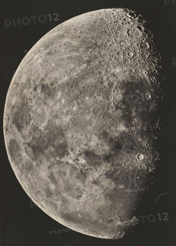 View of the moon, Photographie lunaire obtenue a l'observatoire de Paris, page, photomechanical print, inscription: 'Société Belge d'Astronomie Atlas Lunaire Pl. B.', inscription: '1896. Février 23. _ 6.H. 5M. Temps Moyen de Paris', maker: Loewy et Puiseux, maker: Maurice Loewy, maker: Pierre Henri Puiseux, maker: J. Heuse, 1896-02-23 - in or before 1898, paper, photoaquatint, height 193 mm x width 131 mm, moon as celestial body, A close-up view of a large cratered celestial surface occupying most of the frame against a dark background, showing varied textures from smooth, lighter plains to heavily pockmarked, shadowed regions with numerous circular depressions and raised rims, subtle tonal gradations across the terrain, visible ridges and shadows accentuating depth, and a curved limb delineating the edge of the sphere.