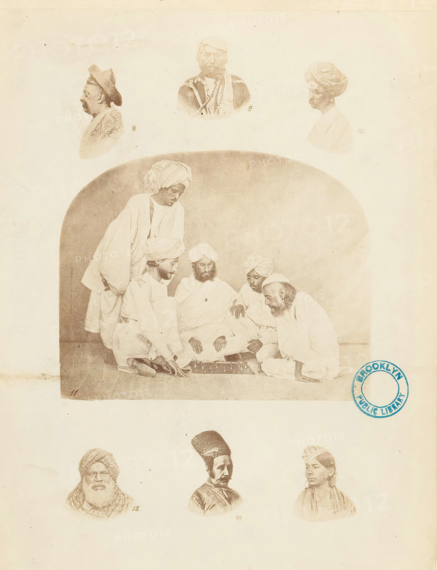 Collection of portraits and a company of Indian men illustrating various types of turbans, Turbans. ornamented, &c., photograph, page, inscription: 'PL. II., Costume-Illustrations', collector's mark: 'Brooklyn Public Library', printer (person): William H. Griggs, c. 1861 - in or before 1866, William H. Griggs, photographer, printer (person), paper, albumen print, height 260 mm x width 205 mm, historical persons, head-gear: turban, A sepia-toned image shows a large central scene of men seated on the floor around a low board, with turbans and loose robes, one man leaning forward and another standing behind them within a rounded-arch backdrop. Above this scene are three portrait busts of men facing different directions, each with distinct headwear. Below the central scene are three more portrait busts of men arranged in a row, each with different facial hair and head coverings. A circular blue stamp appears near the right edge overlapping the central scene. The page has a pale background ...
