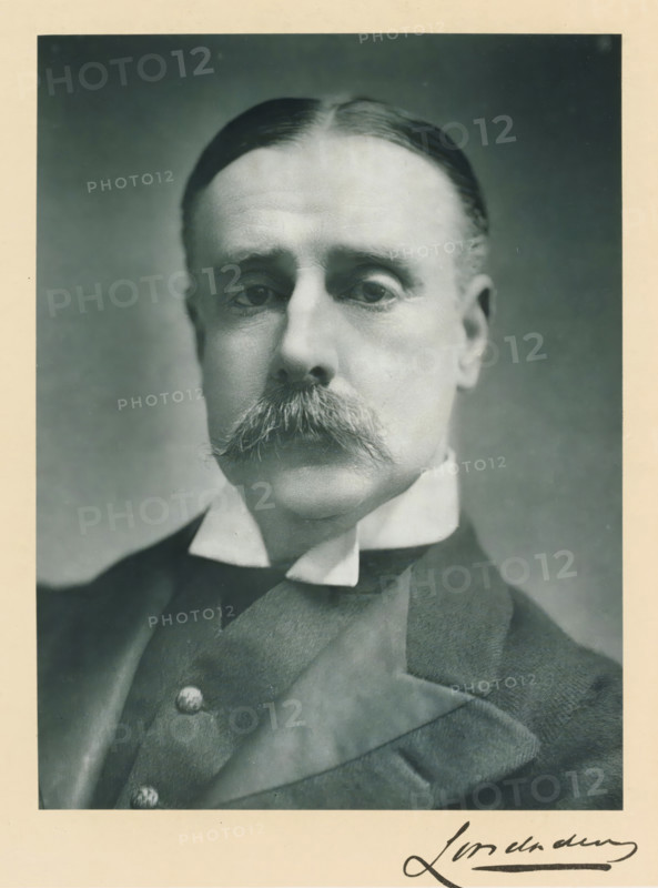 The most noble the marquis of Londonderry, KG, photograph, page, inscription: '55, Baker St, London, W.', annotation, photographer: Elliott & Fry, c. 1893 - c. 1903, paper, carbon print, height 228 mm x width 171 mm, Person, Charles Stewart Vane-Tempest-Stewart, historical persons (portraits and scenes from the life) ((full) bust portrait), A black and white portrait of an older man shown from the shoulders up, with neatly combed hair parted in the middle, a prominent bushy mustache, and a high stiff collar visible above a dark suit jacket and waistcoat with visible buttons.