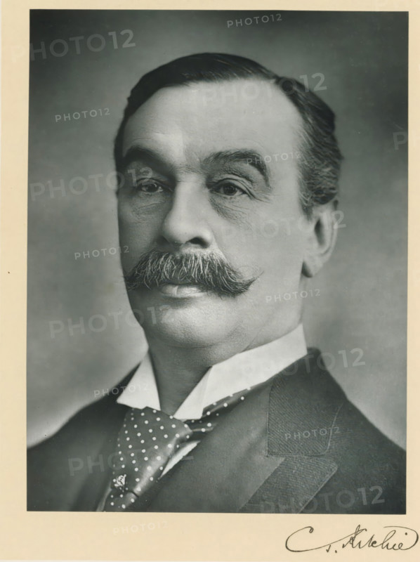 The right honorable Charles Thompson Ritchie, photograph, page, inscription: '263 Oxford St. London, W.', annotation, photographer: Herbert Rose Barraud, London, c. 1893 - c. 1903, paper, carbon print, height 228 mm x width 171 mm, Person, Charles Thomson Ritchie, historical persons (portraits and scenes from the life) ((full) bust portrait), A black and white portrait of an older man from the shoulders up showing a neatly combed dark hair, arched eyebrows, and a prominent curled mustache. His face shows fine wrinkles around the eyes and cheeks. He wears a high white collar, a dark polka-dotted necktie, and a dark suit jacket with a visible lapel. The background is plain and softly shaded, and there is a light border around the photograph.