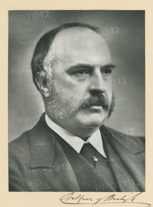 The right honorable lord Balfour of Burleigh KT, photograph, page, annotation, inscription: '36, Pall Mall, London, SW.', photographer: Melhuish & Gale, c. 1893 - c. 1903, paper, carbon print, height 227 mm x width 171 mm, Person, Alexander Bruce, historical persons (portraits and scenes from the life) ((full) bust portrait), A black-and-white portrait of an older man shown from the shoulders up, facing slightly to the right, with a receding hairline and short hair at the sides, prominent bushy sideburns and a thick mustache, visible facial wrinkles around the eyes and cheeks, wearing a dark suit jacket, vest, white shirt, and dark tie, against a plain neutral background with a light border around the image.