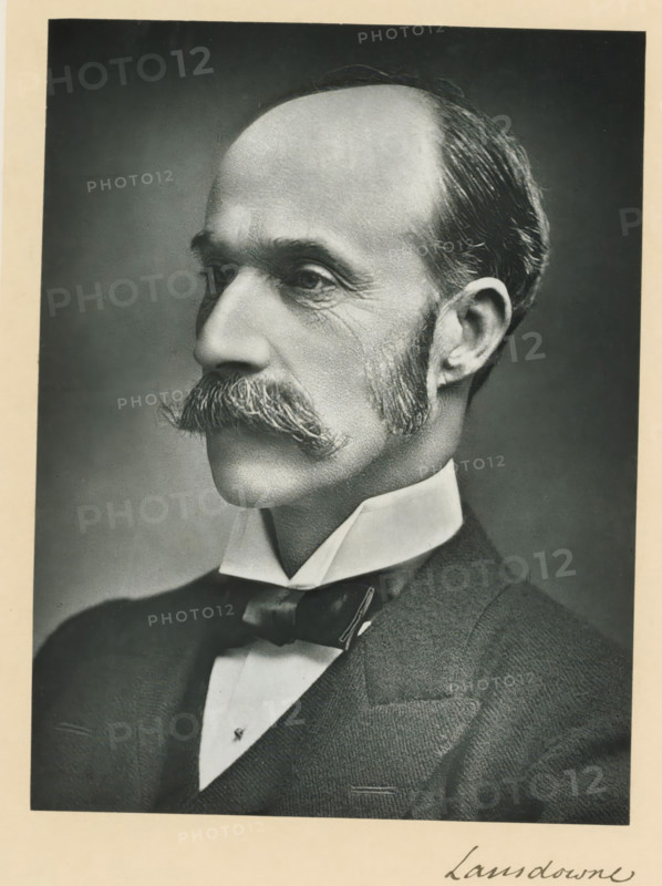 The most noble the marquis of Lansdowne, KG, photograph, page, inscription: '17, Baker St, London, W.', annotation, photographer: Russell & Sons, c. 1893 - c. 1903, paper, carbon print, height 228 mm x width 171 mm, Person, Henry Petty-Fitzmaurice (5th Marquess of Lansdowne), historical persons (portraits and scenes from the life) ((full) bust portrait), A black-and-white portrait of a middle-aged man shown in profile from the shoulders up, with a high forehead and receding hairline, neatly combed hair at the sides and back, prominent mustache with bushy ends, trimmed sideburns, and visible facial wrinkles around the eyes and cheeks; he is wearing a high collared shirt and a bow tie beneath a dark suit jacket, and the image is framed by a light border.