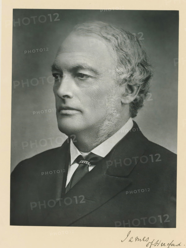 The right honorable lord James of Hereford, photograph, page, annotation, inscription: '25, Old Bond St. London, W.', photographer: Bassano & Co., London, c. 1893 - c. 1903, paper, carbon print, height 227 mm x width 171 mm, Person, Henry James, historical persons (portraits and scenes from the life) ((full) bust portrait), A black and white portrait photograph of an older man shown in profile facing left, with short wavy hair and sideburns, wearing a dark suit jacket, a white shirt with a visible collar, and a necktie secured with a decorative tie clasp; the background is plain and shaded, and the image is bordered by a lighter matte.