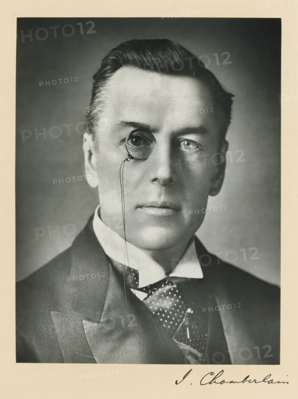 The right honorable Joseph Chamberlain, photograph, page, annotation, inscription: '17, Baker St, London, W.', photographer: Russell & Sons, c. 1893 - c. 1903, paper, carbon print, height 228 mm x width 171 mm, Person, Joseph Chamberlain, historical persons (portraits and scenes from the life) ((full) bust portrait), monocle, single lorgnette, A black-and-white portrait of a man from the shoulders up wearing a dark suit jacket, a high-collared shirt, and a patterned necktie, his hair neatly combed back, his face centered and looking forward, one eye shown through a round monocle attached to a thin cord, the background plain and evenly shaded.