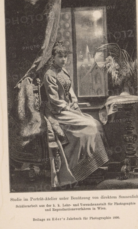 Studio portrait of an unknown woman, page, photomechanical print, monogram: 'AC', inscription: 'Studie im Porträt-Atelier unter Benützung von direktem Sonnenlicht., Beilage zu Eder's Jahbruch für Photographie 1890', maker: KK Lehr- and Versuchsanstalt für Photographie, c. 1885 - in or before 1890, KK Lehr- und Versuchsanstalt für Photographie, paper, autotypie, height 140 mm x width 93 mm, Print on twenty-fifth unnumbered page after page 400., historical persons - BB - woman, A seated woman wearing a long, high-collared dress with a fitted bodice and full skirt sits sideways on a carved wooden chair draped with a patterned fabric, her hands folded in her lap and her hair styled up; behind her is a tall window showing a bright circular light and a faint architectural silhouette, a heavy curtain hangs to one side, and a table with a cloth and a vase of long, arching leaves stands nearby, the scene rendered in a monochrome, stippled illustration style.