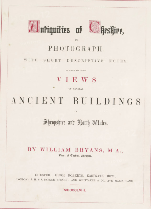 Antiquities of Cheshire in photograph, with short descriptive notes to which are added views of several ancient building in Shropshire and North Wales, book, writer (clerical worker): William Bryans, publisher: Hugh Roberts, Chester (England), publisher: JH & J. Parker, London, publisher: Whittaker & Co., 1858, writer (clerical worker), biological material, paper, leather, albumen print, moiré marbled paper, height 379 mm x width 285 mm x thickness 20 mm, The image shows an off-white page with a thin double-lined red border and various lines of printed decorative type arranged vertically, including ornate initial blocks in a darker color and several centered headings in different sized fonts; there are areas of red ink used for some lines, a few small spots and faint stains on the paper, and the overall layout is symmetrical with generous margins.